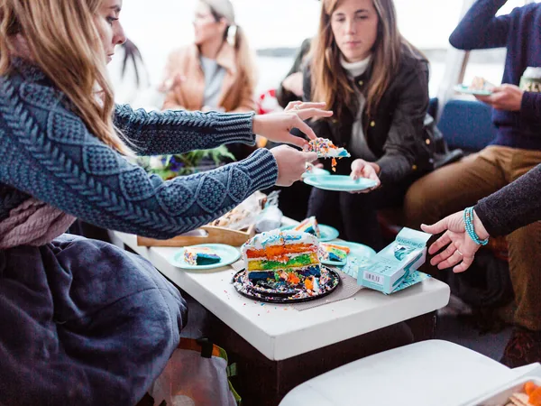 Bachelorette party sharing rainbow cake aboard a Casco Bay charter boat