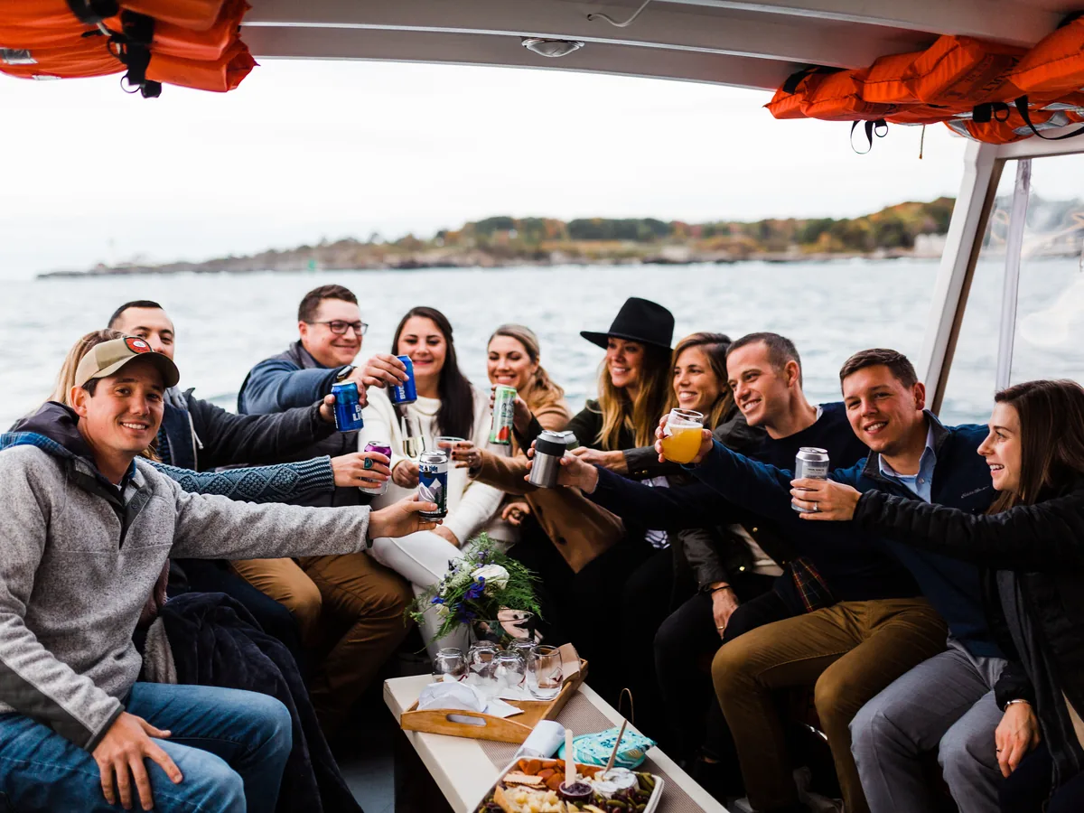 Friends toasting drinks aboard a private boat charter on Casco Bay, Maine